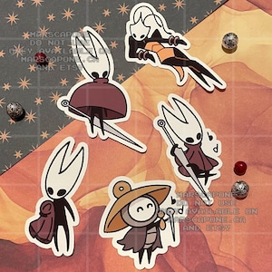 May include: A collection of five die-cut vinyl stickers featuring characters from Hollow Knight, including Hornet and Quirrel. The stickers display various poses and expressions, rendered in a clean, graphic style with white borders on a background.
