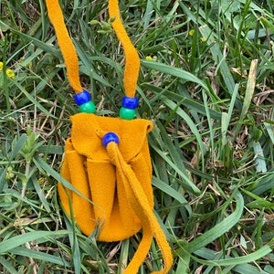 May include: A small, yellow leather pouch with a drawstring closure. The pouch is decorated with blue and green beads and hangs from a yellow leather cord.