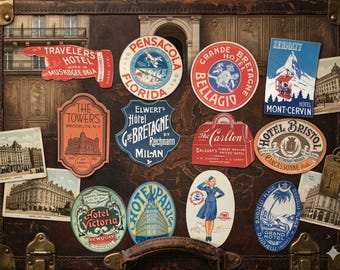 May include: A vintage brown suitcase covered in various travel stickers and postcards. The stickers feature names like Travelers Hotel, Pensacola, Grande Bretagne, Zermatt, The Towers, Hotel Bristol, Hotel Victoria, and Hotel Paris, alongside a TWA illustration.