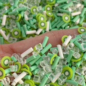 May include: A mix of green and white sprinkles, including kiwi slices, green and white rods, and clear ice cubes.