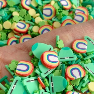 May include: A mix of green, yellow, and rainbow-colored sprinkles. The sprinkles are shaped like shamrocks, hats, and rainbows.