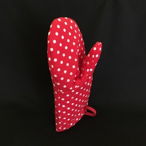 Könnte beinhalten: Roter Ofenhandschuh mit weißen Punkten. Der Handschuh hat eine Aufhängeschlaufe.