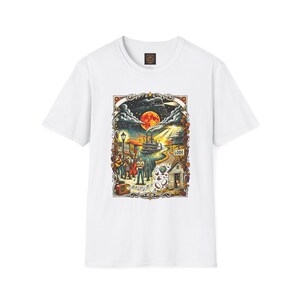 May include: A white short-sleeve t-shirt featuring a colorful graphic print of a river scene with a steamboat, a full moon, a train, and a group of musicians. The illustration includes a sign labeled LODI, a radio, and musical notes.