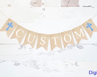 Puede incluir: Un banner de arpillera con la palabra "CUSTOM" en letras blancas y cruces azules en cada extremo. El banner está enhebrado en una cuerda blanca y está colgado contra un fondo de madera blanca.