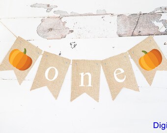 May include: A burlap banner with the word "one" in white letters and two orange pumpkins. The banner is strung with twine and has small silver tacks holding it together.