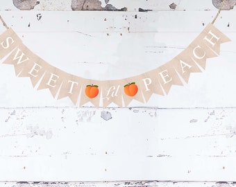 May include: A burlap banner with the words "Sweet as a Peach" in white lettering. The banner has two peach illustrations.