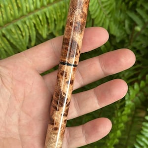 Puede incluir: Un bol&iacute;grafo de madera hecho a mano con un patr&oacute;n de veta de madera natural. El bol&iacute;grafo presenta un acabado pulido con diferentes tonos de marr&oacute;n y beige. Una banda negra acent&uacute;a el centro del bol&iacute;grafo, a&ntilde;adiendo un toque de contraste.