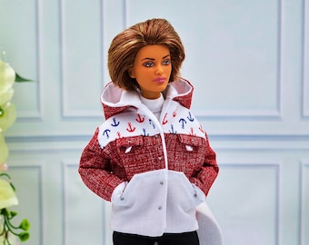 May include: A red and white jacket with a hood and anchor pattern, worn by a doll. The jacket has a red textured body and white accents on the hood and pockets. The hood is decorated with blue and red anchors. The doll is wearing black pants and a white turtleneck.