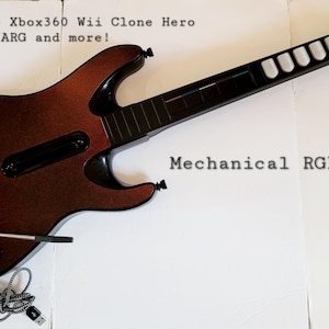 May include: A brown and black guitar-shaped game controller with the text "Mechanical RGB buttons!" and "PS3 PS4 PS5 Xbox360 Wii Clone Hero YARG and more!" The controller has a black neck and white fret buttons.