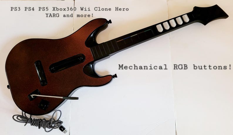 May include: A brown and black guitar-shaped game controller with the text "Mechanical RGB buttons!" and "PS3 PS4 PS5 Xbox360 Wii Clone Hero YARG and more!" The controller has a black neck and white fret buttons.