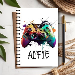 May include: A colorful, abstract paint splatter design featuring a video game controller with the name "Alfie" written below.