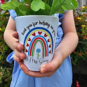 May include: White ceramic planter with a rainbow design and the text "Thank you for helping me grow" and "Mrs. Sams".