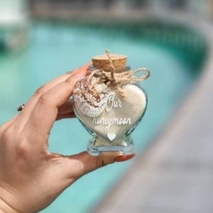 Honeymoon wedding sand. Sweet heart shaped glass bottle jar with a cork. Hand finished with twine and a seashell Personalisation available