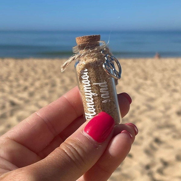 Flitterwochen-Sand. Süße Miniflasche mit einem romantischen Herz, das mit Zwirn befestigt ist. Flitterwochen oder Hochzeitsgeschenk und Andenken