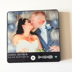 May include: A square, glossy photo print featuring a wedding photo of a couple kissing. The print has a black border and includes the text "JAMES ARTHUR SAY YOU WON'T LET GO" along with a play button, a sound wave, and a heart icon.