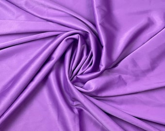 Può includere: Un primo piano di un tessuto liscio e setoso in una vibrante tonalità viola. Il tessuto è drappeggiato e piegato, mostrando la sua texture lussuosa.