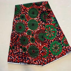 May include: Vibrant fabric with a repeating pattern of green and blue floral and geometric designs on a red background. The fabric has the text "HI-TARGET" and "VERITABLE" printed on it.