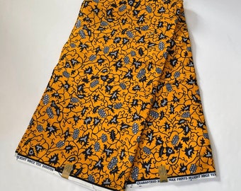 以下が含まれることがあります： 黒と白の花柄の黄色い布。布の端には「WAX PRINTS HLIGHT NBGZ TEX」という文字が印刷されています。