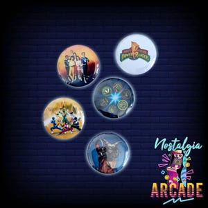 Op de afbeelding: Vijf ronde buttons met Power Rangers-afbeeldingen. Eén toont het Mighty Morphin Power Rangers-logo, een andere het team in actie, één de personages samenstaand, één Rita Repulsa en één toont verschillende munten met symbolen.