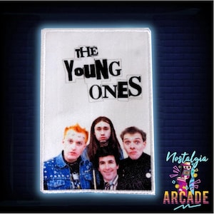 Pode incluir: Um patch retangular com o texto "THE YOUNG ONES" acima de uma foto de quatro pessoas. O patch tem uma borda branca e está sobre um fundo azul escuro. O logotipo Nostalgia Arcade está no canto inferior direito.
