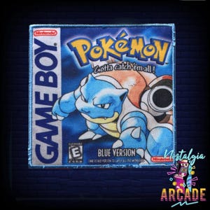May include: A blue and white Game Boy Color cartridge with a blue and white image of a Pokemon character on the front. The cartridge is labelled "Pokemon: Gotta Catch 'Em All!" and "Blue Version".