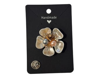 May include: A flower-shaped brooch with a pearl center and crystal accents, mounted on a black card. The brooch has a pin backing. The card reads "Handmade" above a heart symbol.