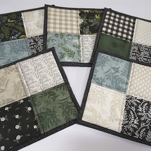May include: Set of four square fabric coasters with a black trim. Each coaster features a different patchwork design with various patterns including floral, geometric, and text. The text on the coasters reads "FAMILY HOME TOGETHER LOVE MILY".