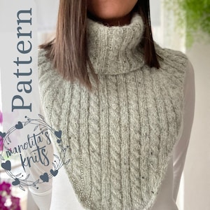 Könnte beinhalten: Ein hellgrauer Strickkragen mit Rippen- und Zopfmuster. Der Kragen hat einen Rollkragen und ist mit "Pattern" und dem Text "manolita's knits" in einem floralen Kranz versehen.