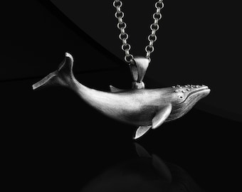 May include: A silver whale pendant necklace. The whale is detailed with a textured surface and has a silver chain.