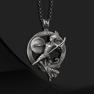 May include: Silver necklace with a pendant featuring a Greek goddess holding a spear and shield, surrounded by a circle with a Greek key design.