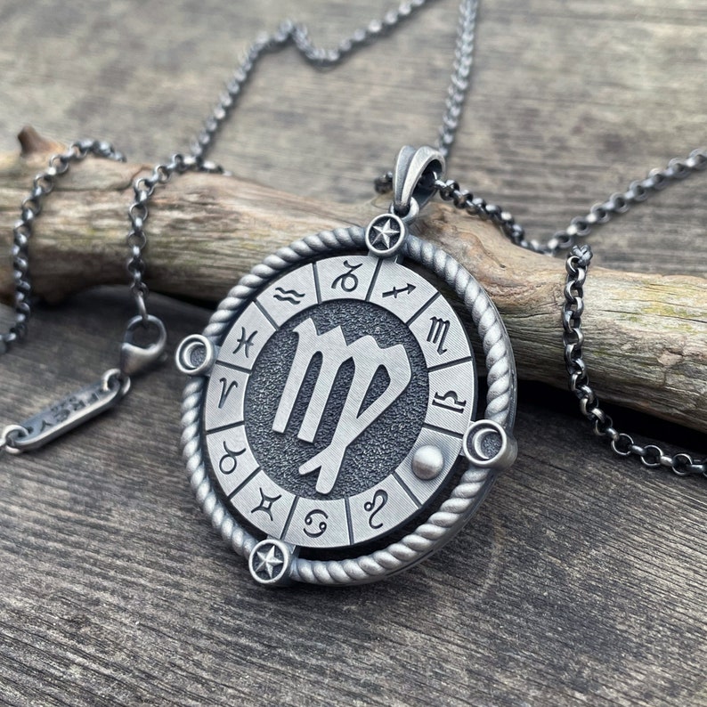 May include: Silver necklace with a round pendant featuring the Virgo zodiac sign surrounded by a circle of zodiac symbols.