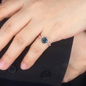 May include: A rose gold ring with a green and black opal stone set in a delicate leaf design.