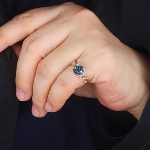 May include: A rose gold ring with a blue and green opal gemstone set in a delicate vine design.