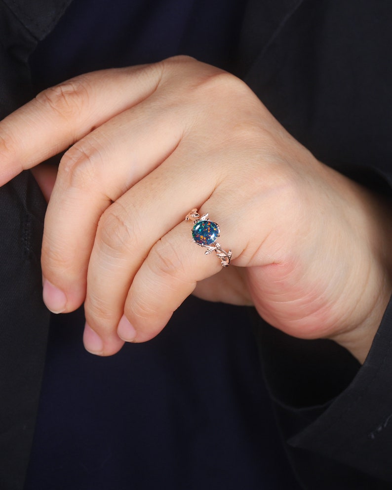 May include: A rose gold ring with a blue and green opal gemstone set in a delicate vine design.