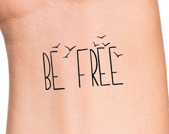 May include: A temporary tattoo on a person's wrist that says "BE FREE" with a flock of birds flying above the text.