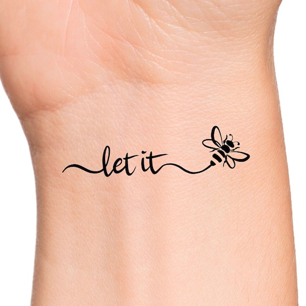 Peut inclure: Un tatouage noir et blanc représentant une abeille avec les mots "let it" écrits en cursive.