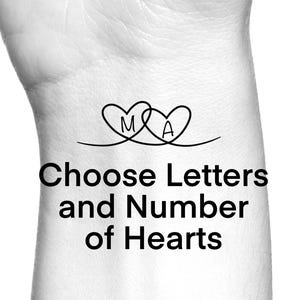 May include: Black and white image of a wrist with a tattoo design. The tattoo features two intertwined heart shapes, each containing a letter, with the letters "M" and "A" visible. Below the hearts, the text reads "Choose Letters and Number of Hearts."