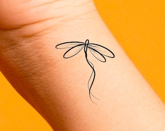 May include: A simple line drawing of a dragonfly tattoo on a person's wrist.