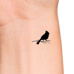 May include: Black silhouette of a cardinal perched on a branch.