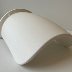 May include: White plastic wall-mounted planter with a curved design. The planter has two holes on the back for hanging.