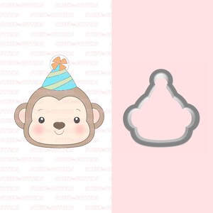 May include: A cookie cutter in the shape of a monkey wearing a party hat. The monkey has brown fur, a pink nose, and big brown eyes. The party hat is blue and green with a yellow star on top.