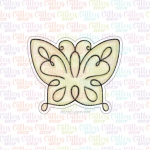 May include: A yellow butterfly cookie cutter with intricate details. The cutter is outlined in black and has a delicate, whimsical design. The text "2022 THE CUTTERS SHOP" is printed at the bottom of the cutter.