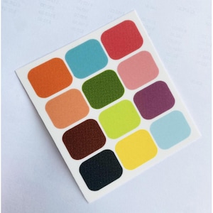 May include: A sheet of 12 colourful, textured, rounded square stickers. The stickers are in shades of orange, pink, green, brown, yellow, blue, and red.