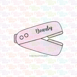 May include: A pink and white plastic stapler with the word "Beauty" written on it. The stapler is open and has two holes for staples.