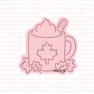 May include: A light pink cookie cutter shaped like a mug filled with whipped cream and a cinnamon stick, featuring a maple leaf design on the front and surrounded by small leaves at the base, with the text S4UC2026 printed on the bottom right.