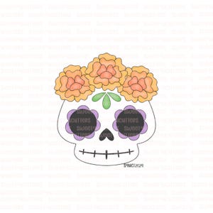 May include: A white sugar skull cookie cutter with a floral design. The skull has black eyes, a purple flower design around the eyes, and a green leaf on the forehead. The skull is topped with three orange marigold flowers.