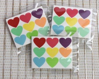 May include: Three sheets of temporary tattoos with rainbow colored hearts. Each sheet has 9 hearts in different shades of red, orange, yellow, green, blue, and purple.