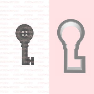 May include: A grey metal cookie cutter in the shape of a key with a button-shaped top. The cutter is shown next to a white background with a pink background behind it.