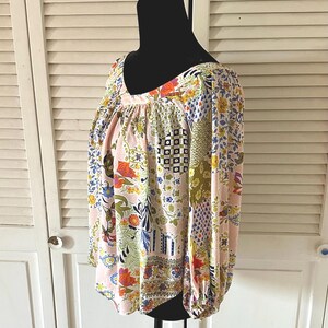 Puede incluir: Una blusa de manga larga con una base de color rosa claro y un patr&oacute;n de patchwork multicolor. El dise&ntilde;o incluye varios motivos florales, formas geom&eacute;tricas y estampados abstractos en tonos azul, amarillo, naranja y verde. Tiene cuello en V.