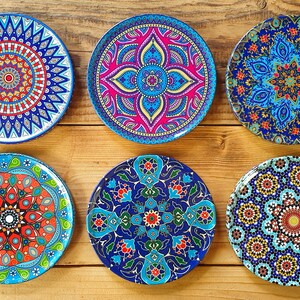 May include: Six decorative ceramic plates with intricate blue, red, and white mandala designs. The plates have a glossy finish and are perfect for adding a touch of bohemian style to your home decor.